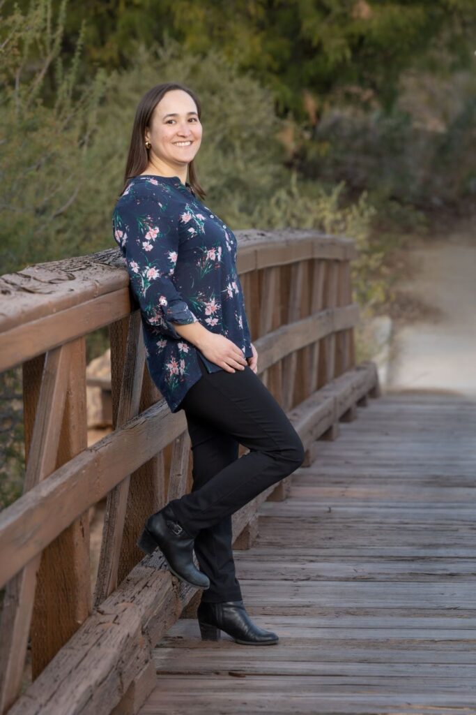 Linda Bain, owner and designer at Bain Marketing. Leaning back against a bridge railing, posing for the camera.